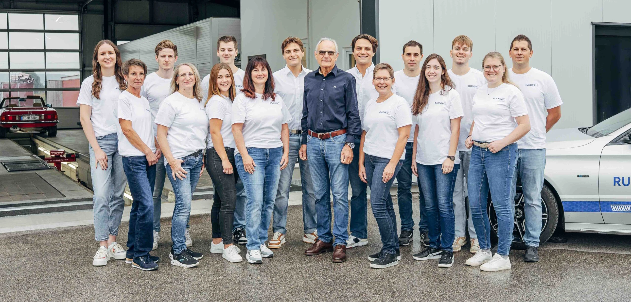 Mitarbeitergruppe von RUCKER² in weißer Firmenkleidung vor der Werkstatt